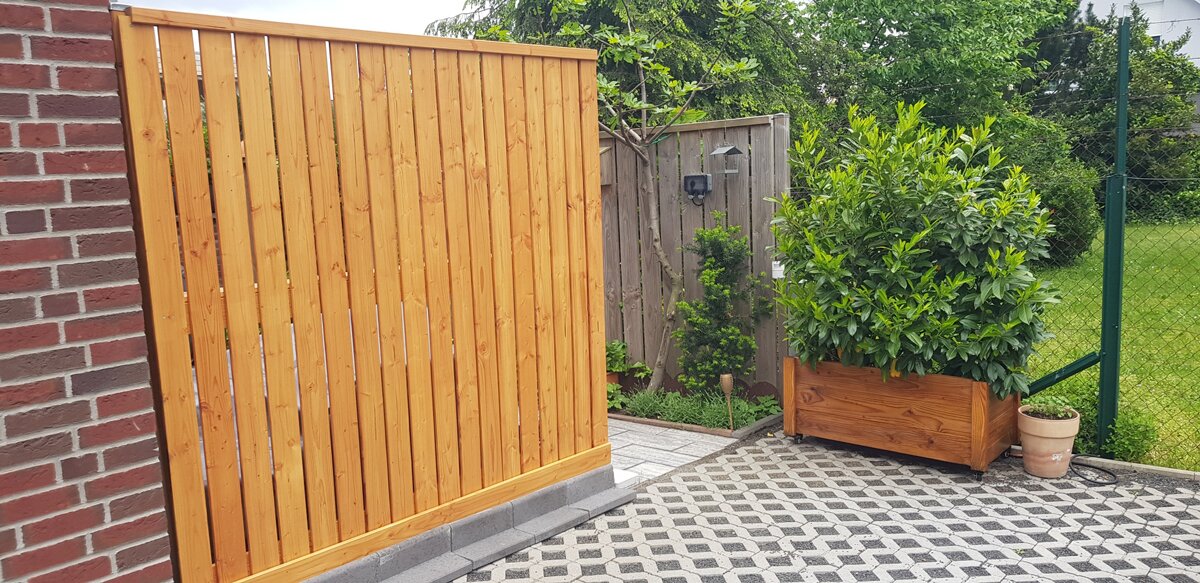 Vorher-Nachher-Vergleich: Vergrauter Gartenzaun und frisch behandeltes Holz nach Anwendung des Nanoprotect Holzpflege Systems.